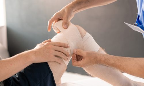 hands-of-clinician-wrapping-right-knee-of-patient-2021-09-24-03-21-50-utc
